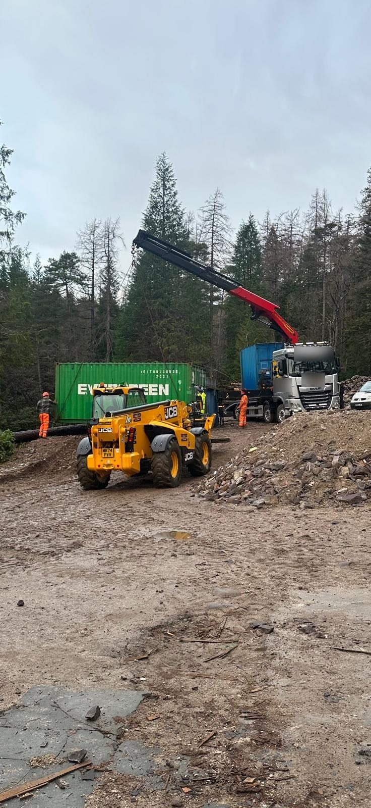 Hi-ab wagon lifting site containers into a forest clearing